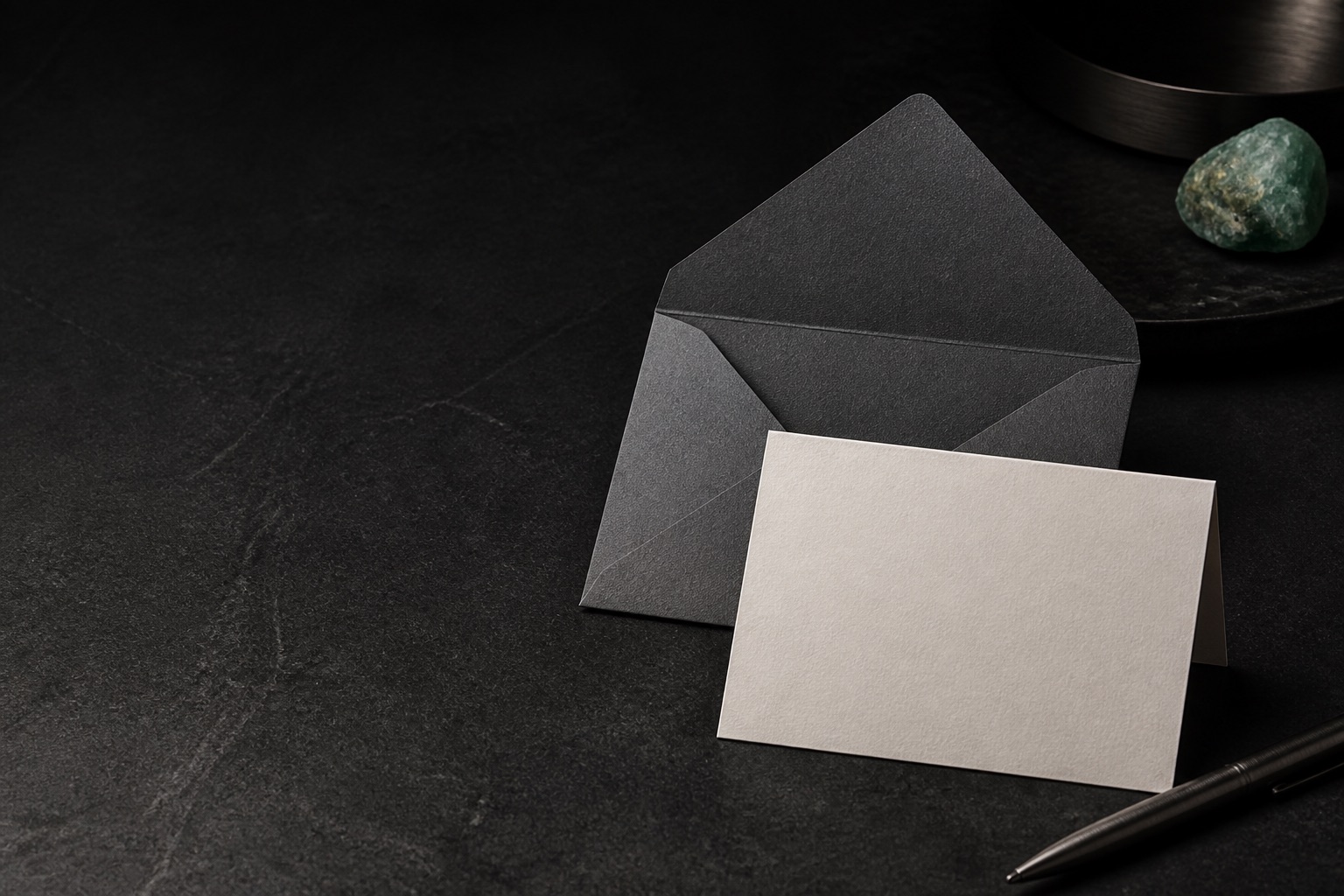 An unmarked note card and envelope on a dark work surface
